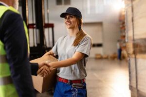 woman in a warehouse shaking hands with her foreman