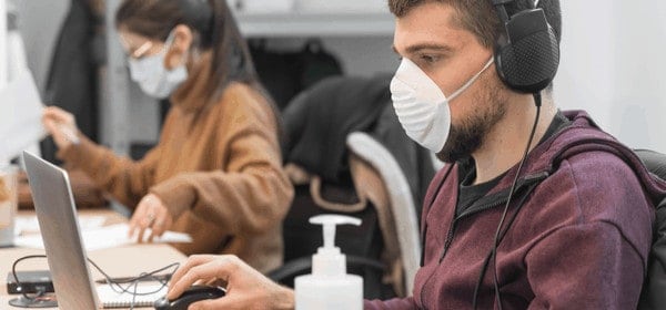 Employees using laptops while wearing face masks
