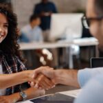 Young woman shaking hands with recruiter after a successful staffing agency interview.