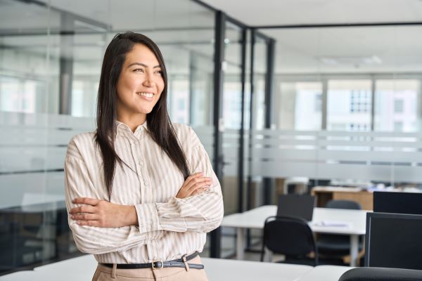 Smiling woman in office standing in front of desk.